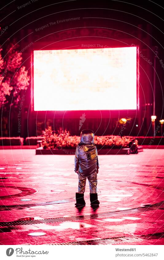Spaceman on a square at night attracted by shining projection screen astronaut astronauts plaza places Public Square Projection Screen city town cities towns