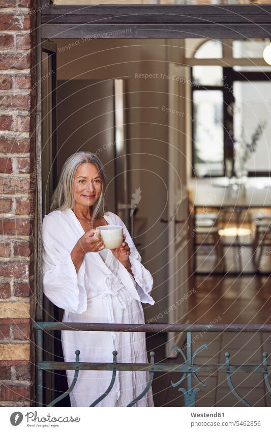 Smiling woman drinking tea in balcony Germany outdoors location shots outdoor shot outdoor shots day daylight shot daylight shots day shots daytime front view