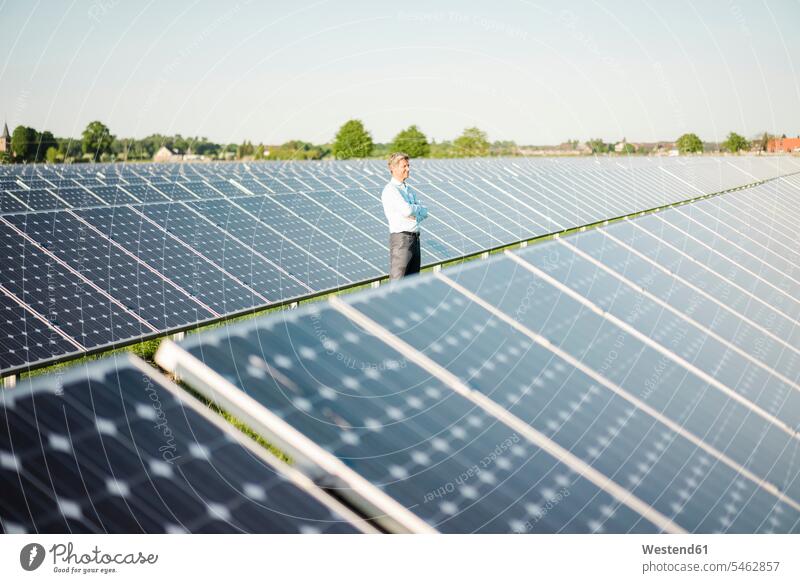 Mature man standing in solar plant alternative energy ecology Solar Power Station technology technologies Technological smiling smile men males Green Energy