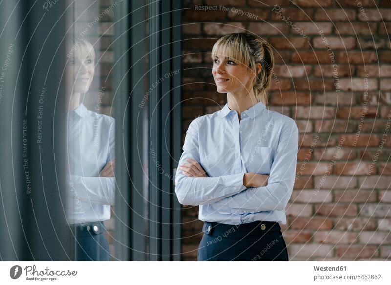 Confident businesswoman looking out of window, with arms crossed Looking Through Window Looking Through A Window looking through glass businesswomen