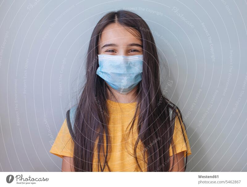 School girl with face mask standing against gray wall color image colour image indoors indoor shot indoor shots interior interior view Interiors day