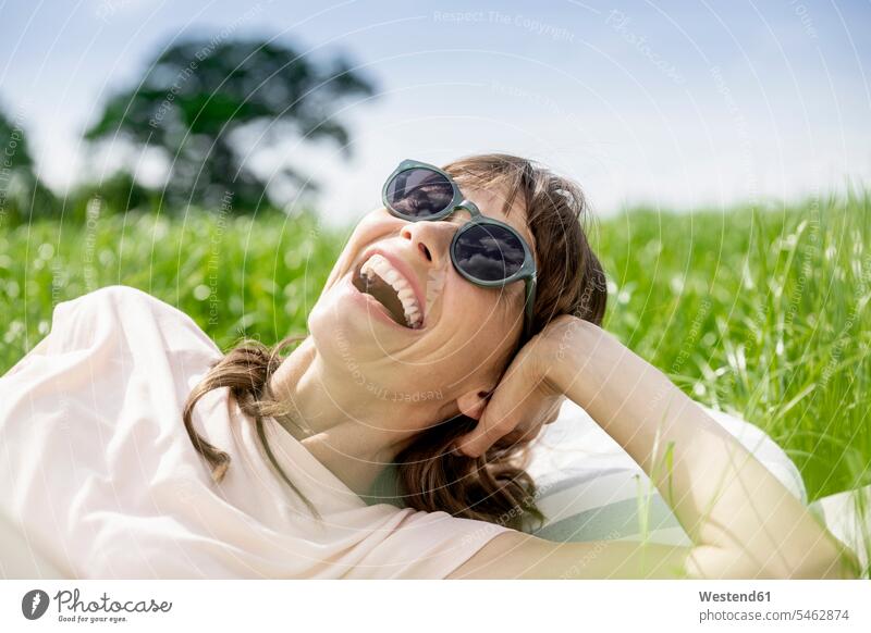 Portrait of laughing relaxed woman lying on a meadow human human being human beings humans person persons adult grown-up grown-ups grownup grownups female