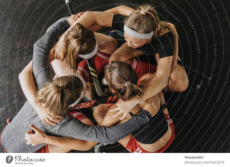 Hockey players huddling while crouching on floor in health club color image colour image Germany indoors indoor shot indoor shots interior interior view