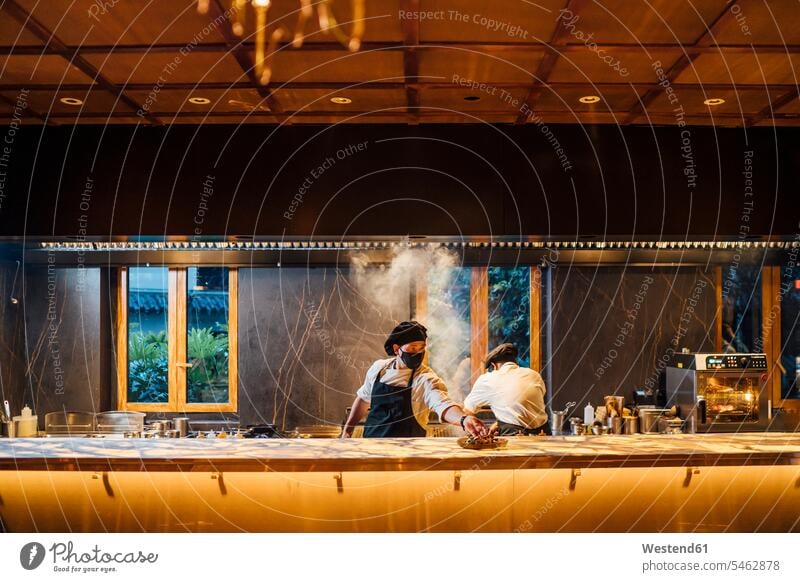 Chefs wearing protective face masks working in restaurant kitchen human human being human beings humans person persons 2 2 people 2 persons two two persons