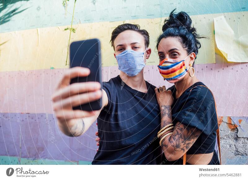 Lesbian couple taking selfie while wearing mask in city color image colour image outdoors location shots outdoor shot outdoor shots day daylight shot