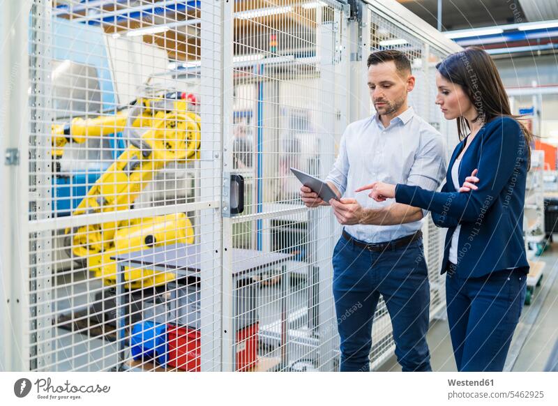 Businessman and businesswoman with tablet talking in modern factory speaking Business man Businessmen Business men factories businesswomen business woman