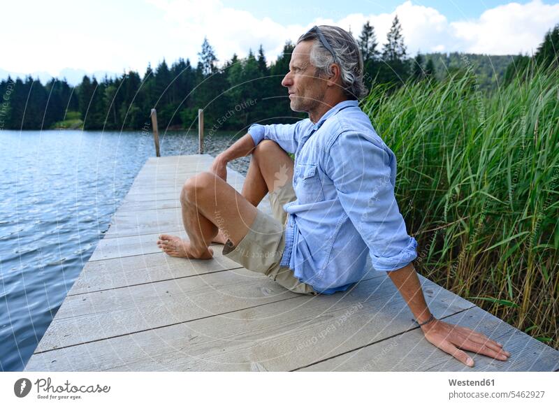 Germany, Mittenwald, mature man relaxing on jetty at lake men males landing stage landing stages lakes relaxation Adults grown-ups grownups adult people persons