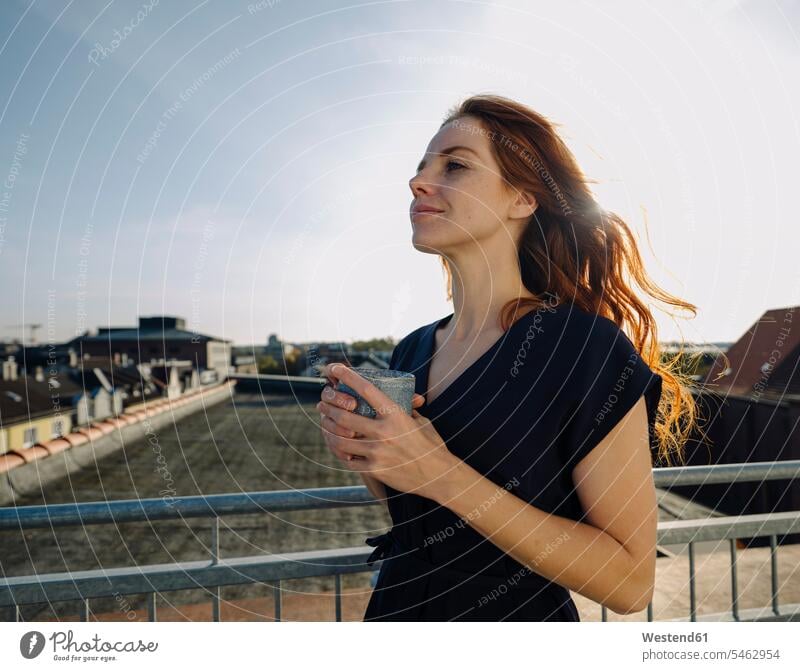 Smiling redheaded woman having a coffee break on rooftop terrace human human being human beings humans person persons caucasian appearance caucasian ethnicity