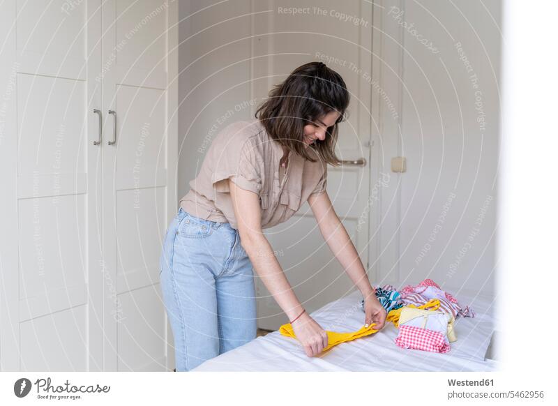 Young woman placing clothes on bed human human being human beings humans person persons caucasian appearance caucasian ethnicity european 1 one person only