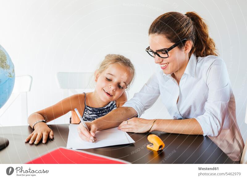 Teacher helping schoolgirl at desk writing on paper human human being human beings humans person persons caucasian appearance caucasian ethnicity european 2
