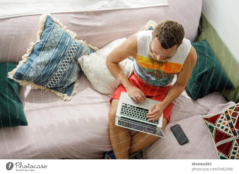 Man using laptop on sofa in living room at home color image colour image indoors indoor shot indoor shots interior interior view Interiors day daylight shot