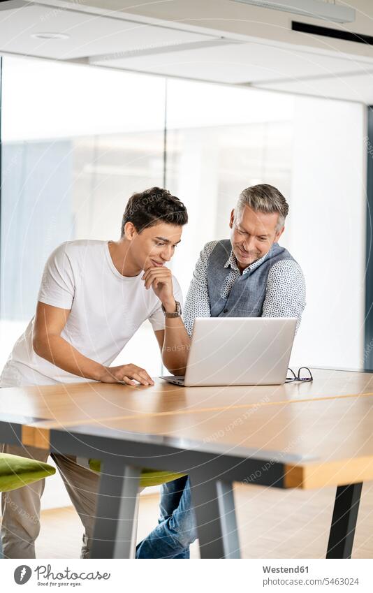 Senior businessman working with young colleague, using laptop human human being human beings humans person persons caucasian appearance caucasian ethnicity