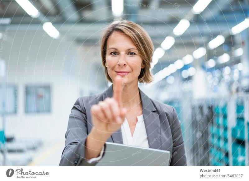 Portrait of businesswoman with tablet in a modern factory touching virtual screen human human being human beings humans person persons caucasian appearance
