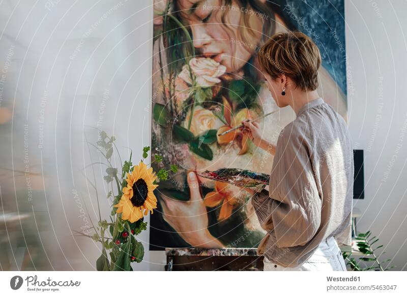 Mid adult female artist painting on canvas in studio color image colour image painter painters indoors indoor shot indoor shots interior interior view Interiors