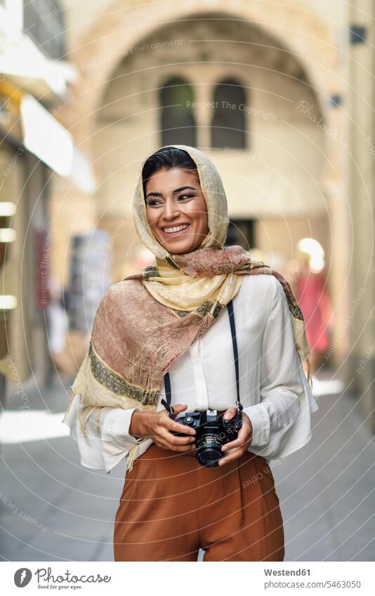 Spain, Granada, young Arab tourist woman wearing hijab, using camera during sightseeing in the city headscarf head scarf head scarves Head Scarf head cloths