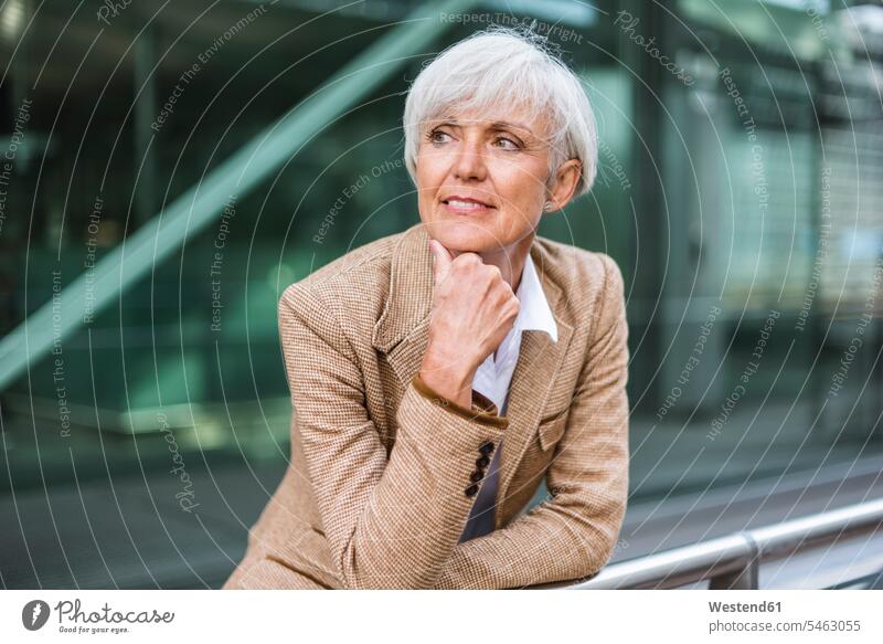 Portrait of senior businesswoman leaning on railing in the city looking around businesswomen business woman business women portrait portraits town cities towns