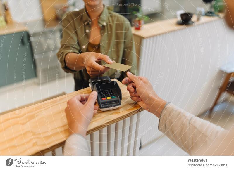 Midsection of female entrepreneur giving credit card to customer at checkout in cafe color image colour image indoors indoor shot indoor shots interior