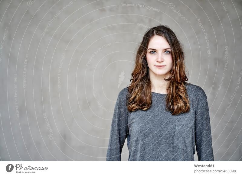 Portrait of confident young woman in front of grey wall females women confidence portrait portraits Adults grown-ups grownups adult people persons human being