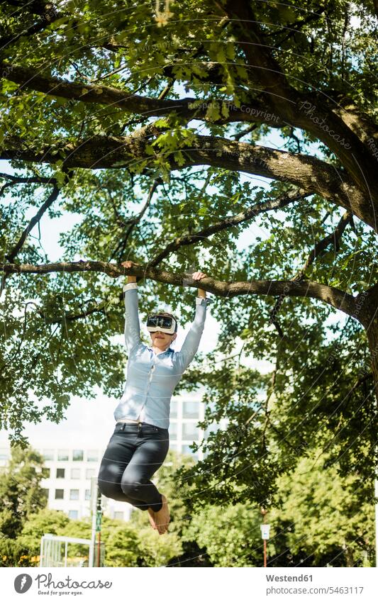 Woman in urban park hanging at branch of a tree wearing VR glasses Virtual Reality Glasses Virtual-Reality Glasses virtual reality headset vr headset vr goggles