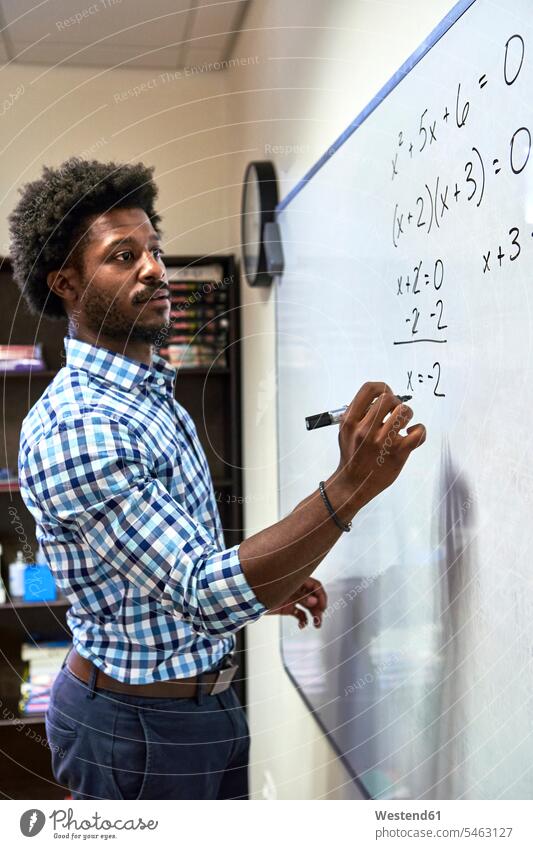 Maths teacher writing a formula on a whiteboard Occupation Work job jobs profession professional occupation blackboards shirts pencil pencils pens calculate