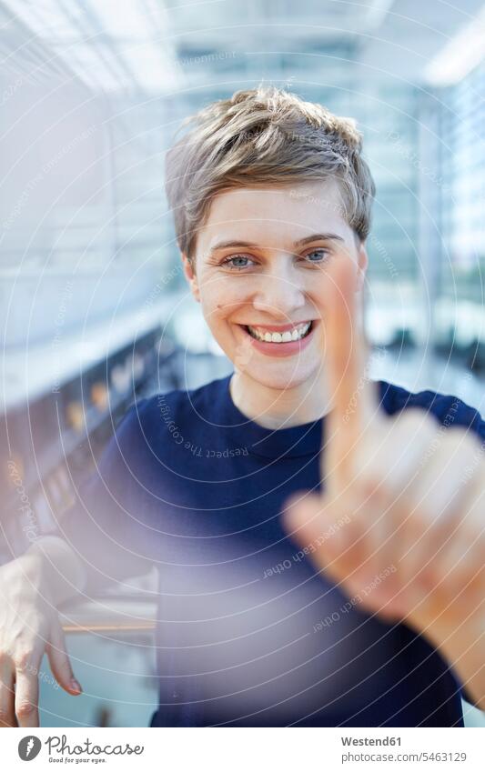 Portrait of blond businesswoman touching at glass pane looking eyeing glass panes blond hair blonde hair portrait portraits females women businesswomen