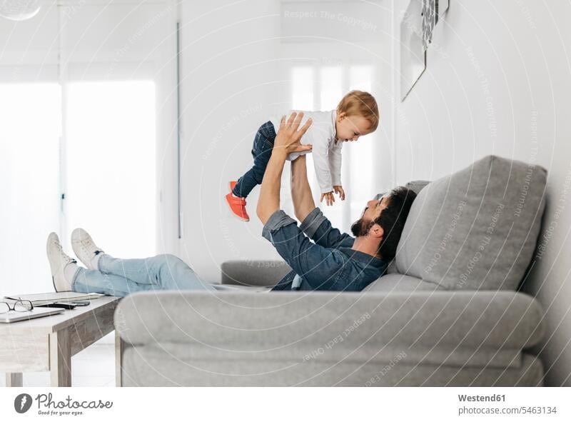Father playing with his daughter at home Pretending To Fly Pretending to be a plane father pa fathers daddy dads papa childhood couch settee sofa sofas couches