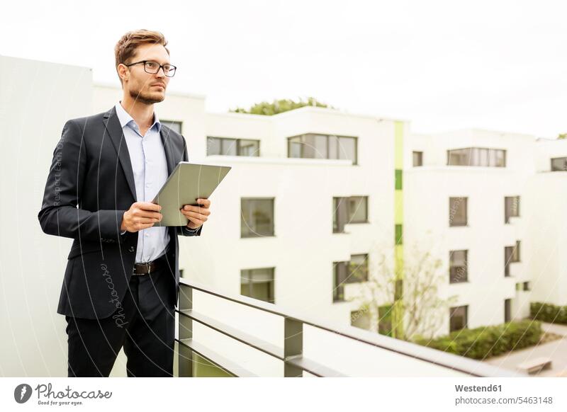 Businessman with tablet standing on balcony in a development area human human being human beings humans person persons caucasian appearance caucasian ethnicity