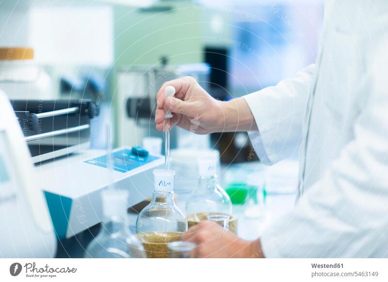 Lab technician experimenting in lab laboratory workplace work place place of work effort attempt hand human hand hands human hands flask recipient