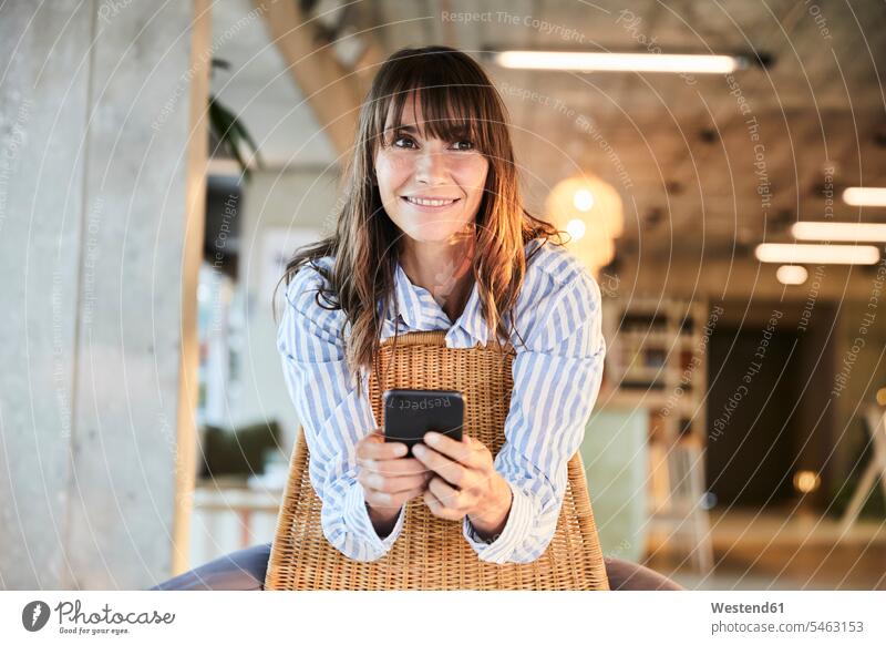 Mature woman smiling while using smart phone sitting at home color image colour image indoors indoor shot indoor shots interior interior view Interiors day