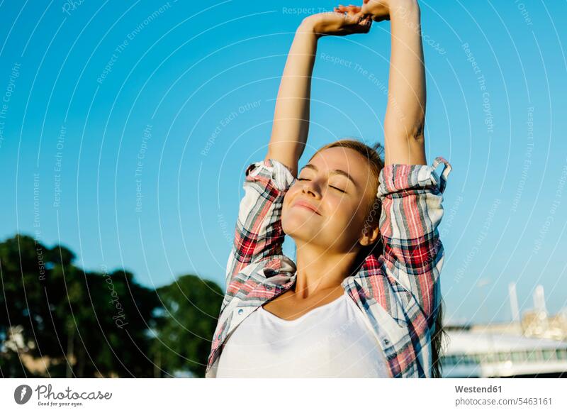 Woman with arms raised stretching hand standing against clear sky on sunny day color image colour image outdoors location shots outdoor shot outdoor shots