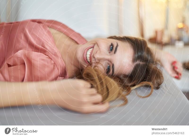 Portrait of happy young woman in dressing gown lying in bed beds females women laying down lie lying down bathrobe happiness portrait portraits smiling smile