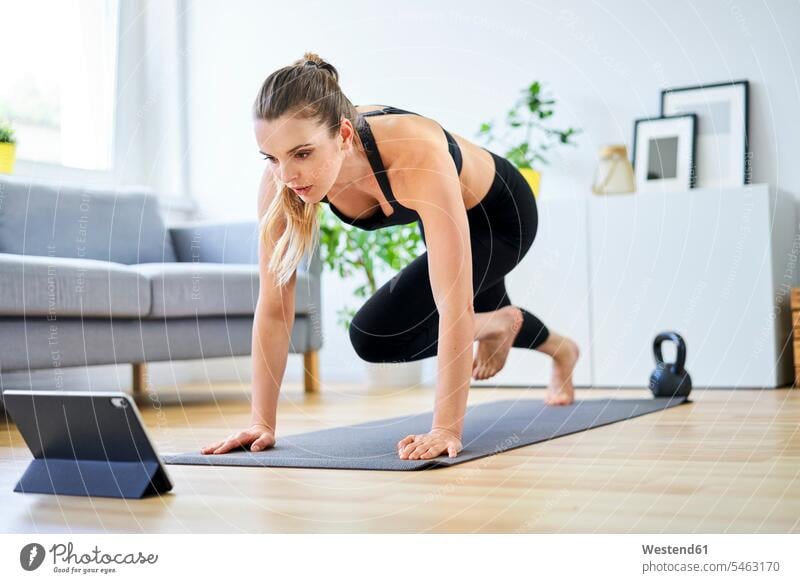 Determined woman learning mountain climber exercise through internet on digital tablet color image colour image indoors indoor shot indoor shots interior