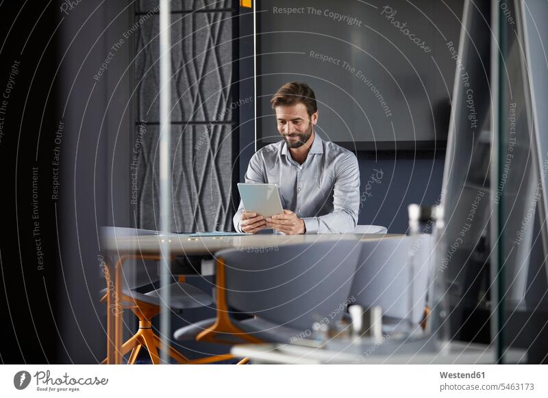 Smiling businessman using digital tablet while sitting in office color image colour image indoors indoor shot indoor shots interior interior view Interiors day