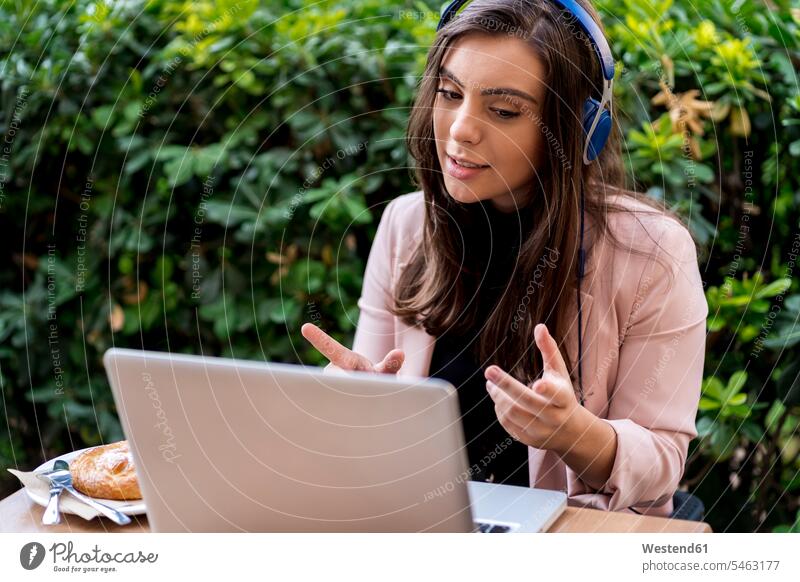 Businesswoman gesturing while video calling through laptop on terrace of cafe color image colour image day daylight shot daylight shots day shots daytime Spain