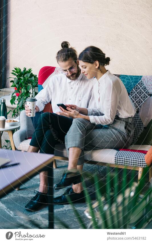 Young couple sitting on a sofa using a smartphone colleague Occupation Work job jobs profession professional occupation business life business world