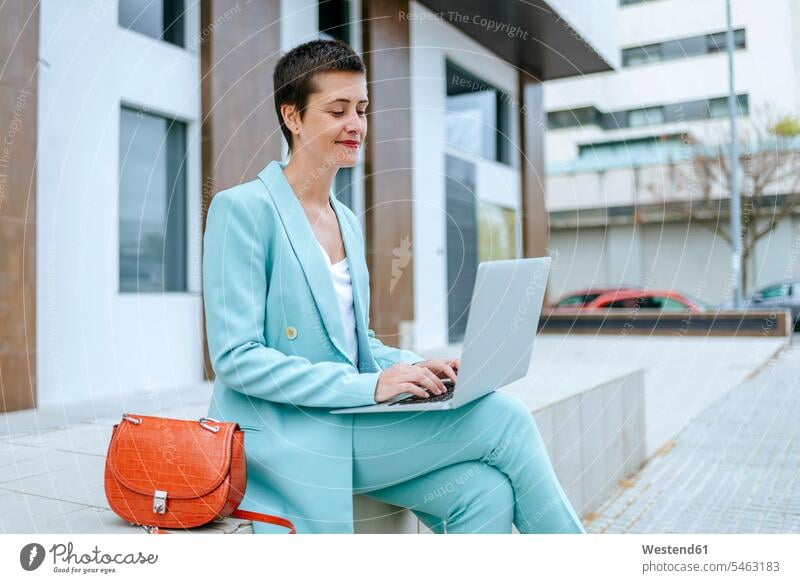 Woman in suit jacket using laptop outdoors woman females women bench benches Laptop Computers laptops notebook use Adults grown-ups grownups adult people
