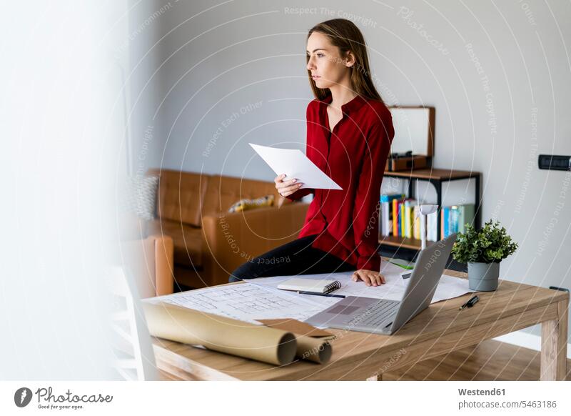 Woman in office holding paper with wind turbine model on table human human being human beings humans person persons caucasian appearance caucasian ethnicity