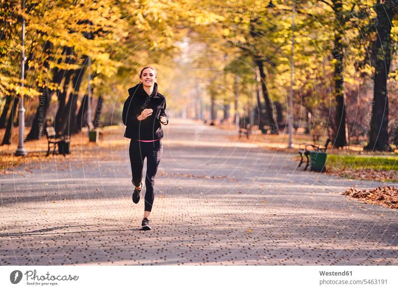 Young woman jogging in autumn forest run smile fall delight enjoyment Pleasant pleasure happy content Contented Emotion pleased Black Color Black Colour