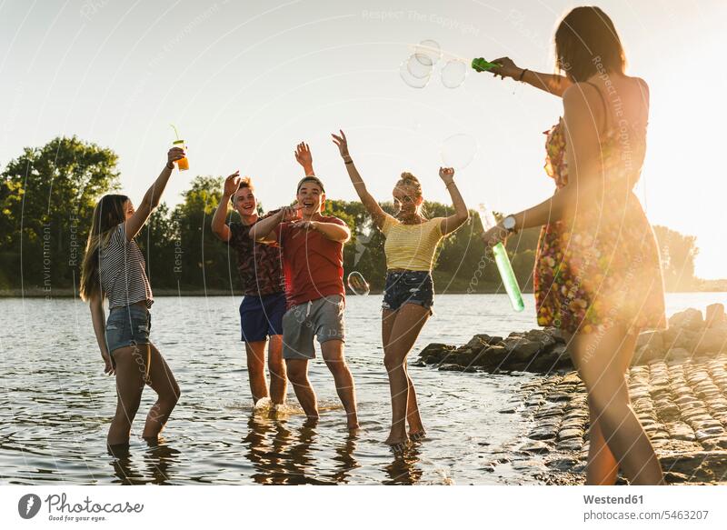 Group of happy friends in a river at sunset mate group of people groups of people River Rivers sunsets sundown happiness friendship persons human being humans