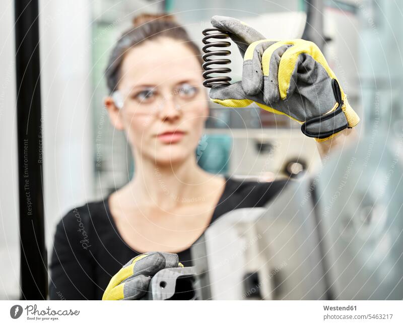 Woman working on a machine, looking on spring producing making brown hair brown haired brown-haired brunette metal metals safety glasses Protective Eyeglasses
