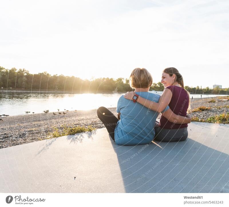 Grandmother and granddaughter sitting at the river after training, watching the sunset Quality Time recreation relaxing Recreational full length full-length