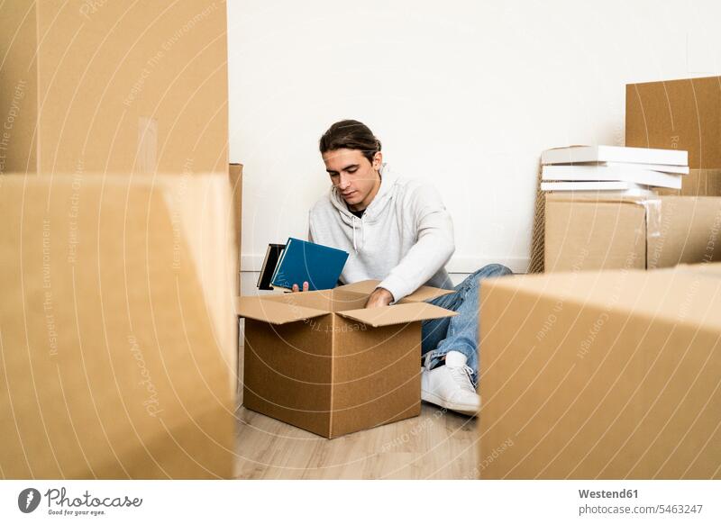 Young man unpacking box while shifting in new apartment color image colour image indoors indoor shot indoor shots interior interior view Interiors day