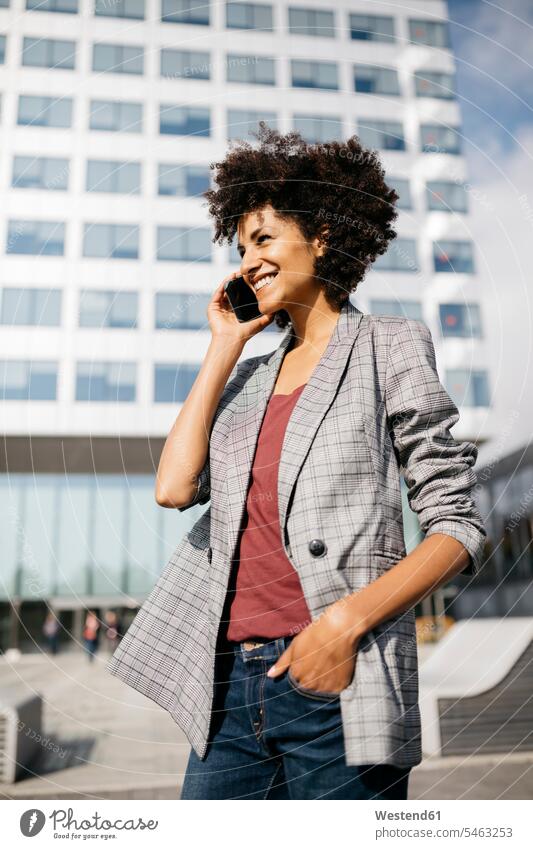 Smiling businesswoman on cell phone outside office building smiling smile businesswomen business woman business women confidence confident mobile phone mobiles
