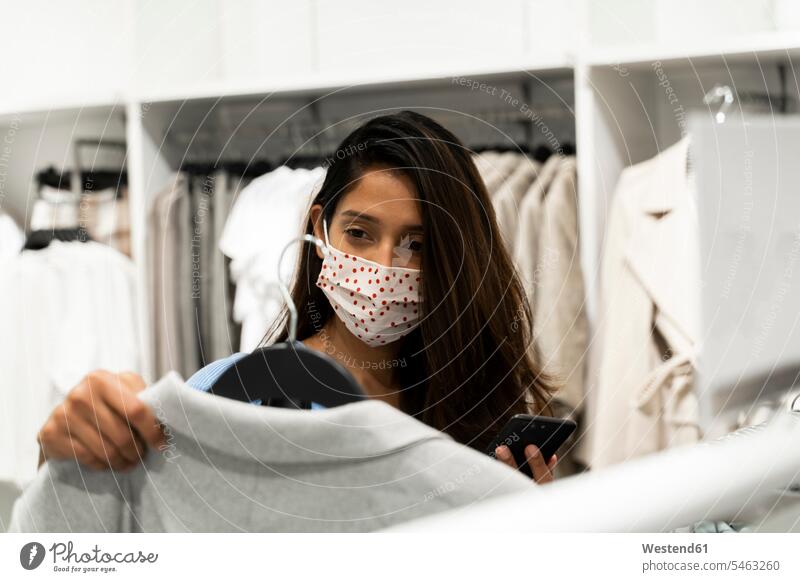 Woman wearing protective mask while looking at clothes in shopping mall color image colour image indoors indoor shot indoor shots interior interior view