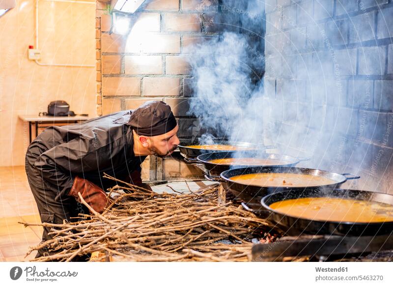Traditional cooking of paella in restaurant kitchen Occupation Work job jobs profession professional occupation Chefs cooks At Work heat Hot Temperature
