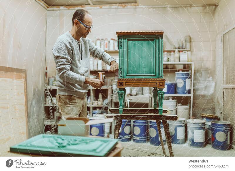 Manual worker repairing furniture while standing at workshop color image colour image indoors indoor shot indoor shots interior interior view Interiors