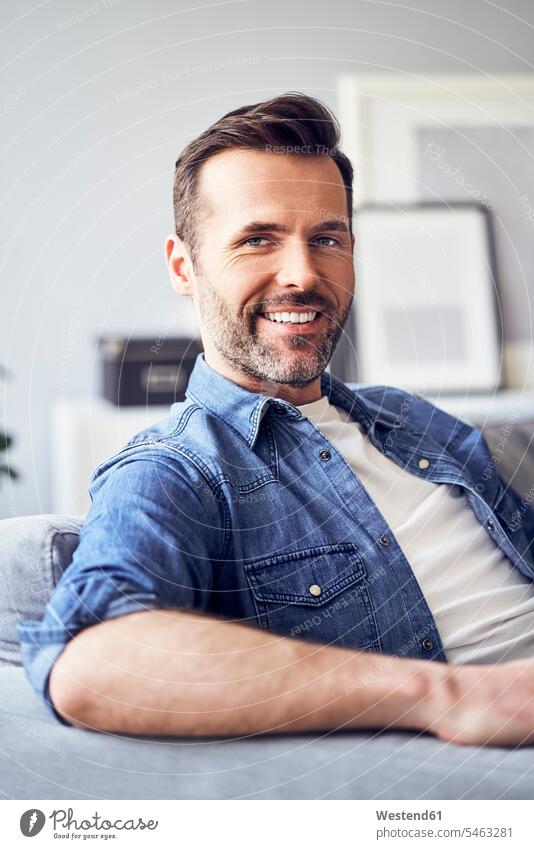 Portrait of smiling man sitting on sofa smile relaxed relaxation Seated men males couch settee sofas couches settees portrait portraits relaxing Adults