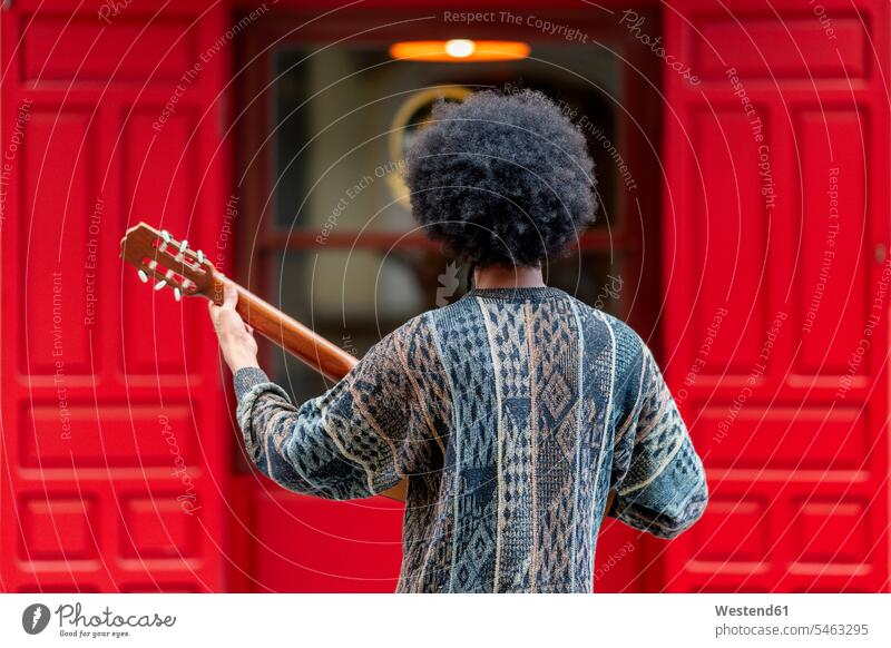 Young man playing guitar while standing in front of building color image colour image Spain leisure activity leisure activities free time leisure time