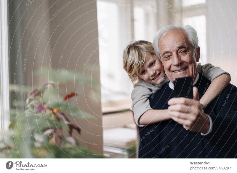 Happy grandfather and grandson using cell phone at home generation windows jumper sweater Sweaters telecommunication phones telephone telephones cell phones