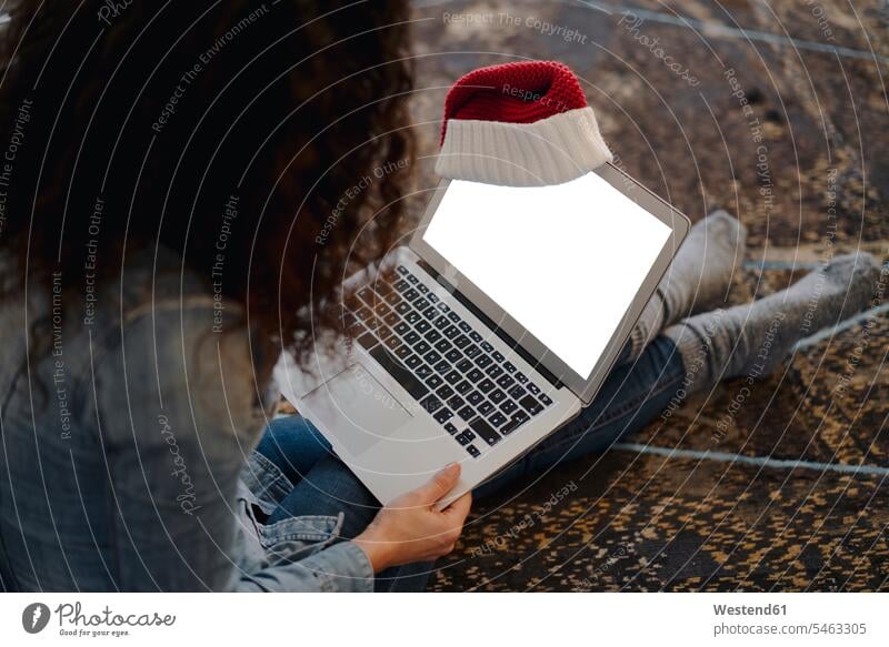 Woman with Santa hat looking for presents online, using laptop human human being human beings humans person persons caucasian appearance caucasian ethnicity